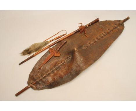 AN AFRICAN SHIELD, late 19th century, the thick eliptical hide body with central boss and bamboo central shaft,  50 1/2" tall