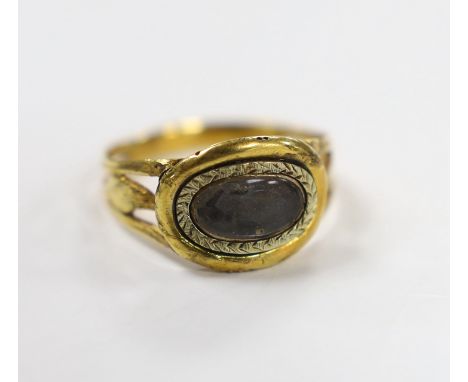 An early 19th century two colour yellow metal mourning ring, with glazed panel and pierced foliate shoulders, size R, gross w