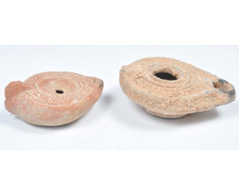 Roman antiquities - Two ancient Roman oil lamps to include a terracotta lamp having a discuss decorated with circular motifs 