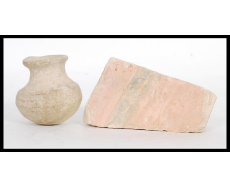 Two ancient Egyptian artefacts to include a plaster fragment of a wall fresco being painted in pink and black along with an u