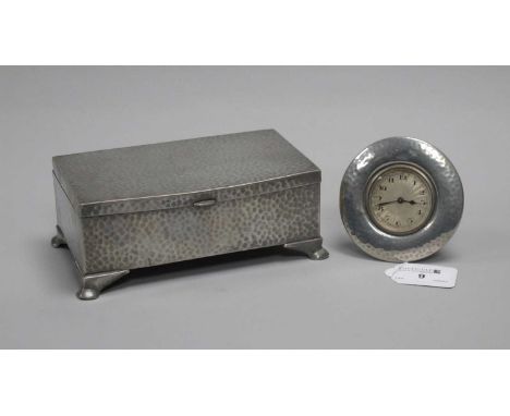 A Tudric Pewter Bedside Clock, the engine turned circular dial with black Arabic numerals, within wide planished circular fra