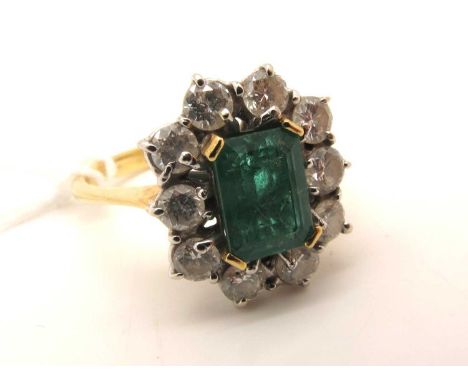 An 18ct Gold Emerald and Diamond Cluster Ring, rectangular claw set to the centre, within brilliant cut diamond set border (f