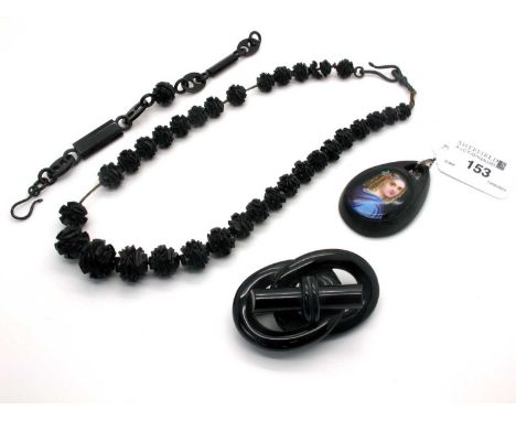 A Large Victorian Jet Brooch, (6.8cm long); A Victorian Pendant, with applied ceramic panel; A Graduated Carved Bead Necklace