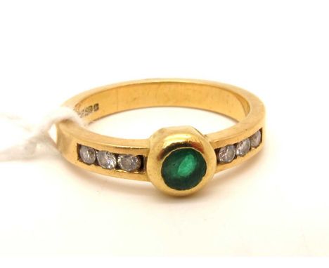 An 18ct Gold Emerald and Diamond Ring, circular collet rubover set to centre, between brilliant cut diamond channel set shoul