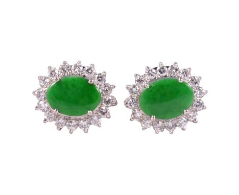 A pair of jade and diamond cluster earrings, each set with an 8.5x6.3mm cabochon cut jade surrounded by sixteen brilliant cut