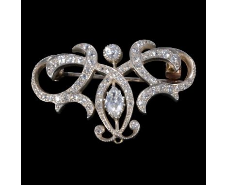 An Art Nouveau style diamond brooch, the marquise cut stone claw set to a white metal bar with a brilliant cut stone above an