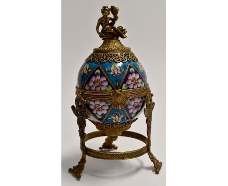Gilt metal mounted egg box, floral enamel decoration with Putto on dolphin finial.Height approx 18cm, diameter 8.3cm approx.