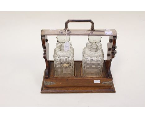 An early 20th Century oak tantalus, fitted with two square cut glass decanters, complete with a George III silver whisky deca