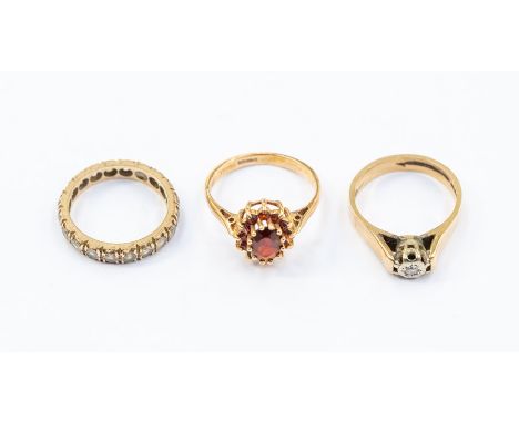 A 9ct gold and diamond ring, size L1/2, along with a 9ct gold and garnet set clustering, size M and an unmarked yellow metal 