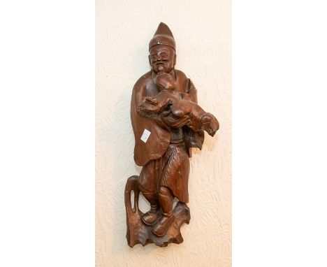 A 19th century Chinese wood carving of an elder carrying child, rustic chisel marks verso, intended for hanging display, H. 5