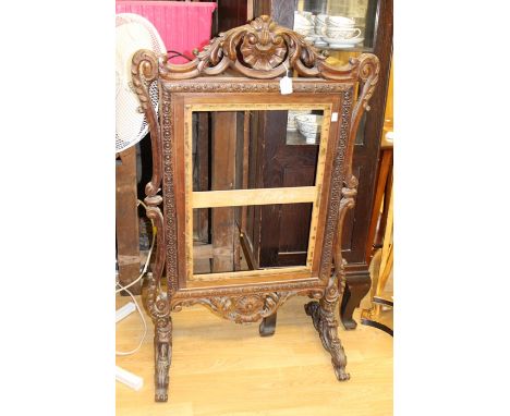 A mid 19th Century rosewood carved firescreen, raised on scroll carved feet (no panel)