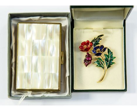 An unused musical powder compact with mother of pearl lid, together with a gilt metal and enamel brooch, the flowers are anem