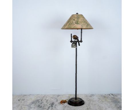 A striking floor lamp featuring a bronze tone parrot perched on a bamboo style base, holding a lantern style light. The lamp 