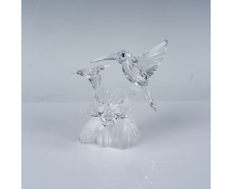Exquisite figurine showcases a Hummingbird hovering delicately over flowers, mounted on a mirrored display base. Swarovski's 