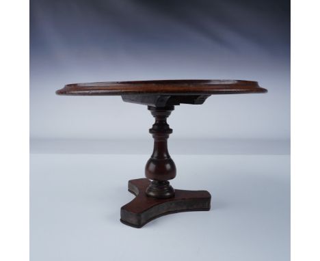 This antique miniature round tilt-top table, crafted from rich mahogany, showcases exquisite craftsmanship typical of the Vic