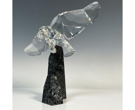 This exquisite faceted clear crystal eagle is depicted mid-flight with talons ready to strike. The eagle is poised above a sc