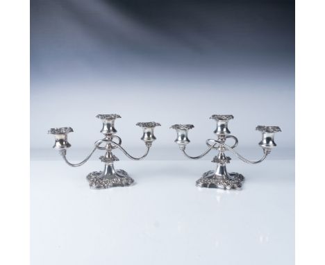 A charming pair of Rococo-style silver-plated candelabras featuring ornate floral and scroll detailing, indicative of the per