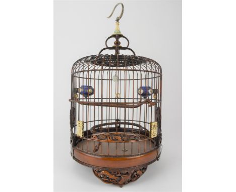 A 20th century Chinese wooden and cane bird cage with a metal hook, a jade and bone finial, bone rings and panels, carved woo
