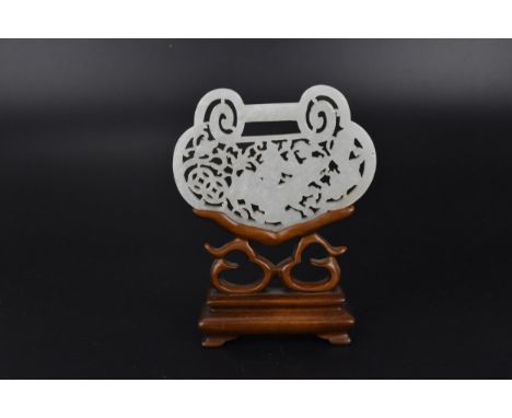 A Chinese late Qing dynasty white jade reticulated plaque on stand, the plaque with lobed edges cantered with a pierced and c