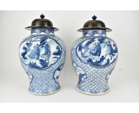 A pair of Chinese Qing dynasty blue and white porcelain vases, 18th century of baluster shape with a ruyi border, the body de