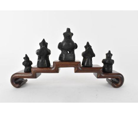 A graduated set of Thai/Burmese bronze opium weights in the form of Hintha birds, the largest 5cm h on a stepped wooden stand