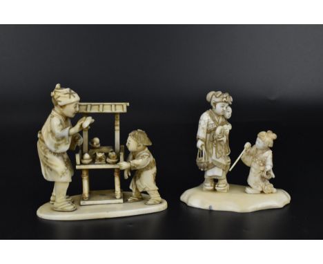 Two Japanese Meiji period okimono, one modelled as a mother with two children, the other as a food stall seller and child, bo