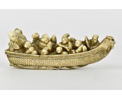 A Japanese Meiji period ivory netsuke of a boat crowed with gods of good fortune, men, women and children, signed to the base