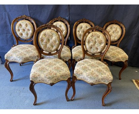 A set of six late Victorian walnut salon chairs, with carved ornament, a button upholstered oval back and serpentine front se