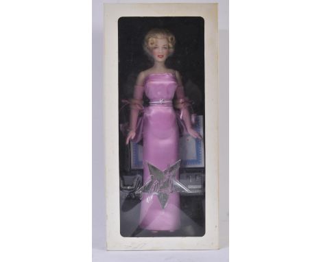 A Franklin Mint made Marilyn Monroe portrait doll. The porcelain doll with pink satin dress, hand painted features and jewell