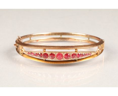 9 carat rose gold ruby stiff bangle set with thirteen graduated rubies6.5cm diameter , weight 9g