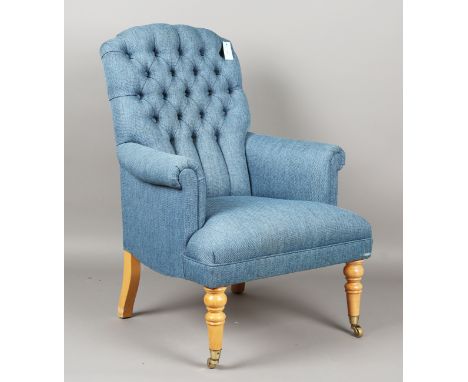 A modern armchair, upholstered in buttoned blue fabric, on turned legs and brass castors, height 103cm, width 75cm.Buyer’s Pr