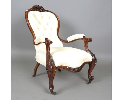 A mid-Victorian walnut showframe armchair, the top rail finely carved with a foliate cartouche, upholstered in cream damask, 