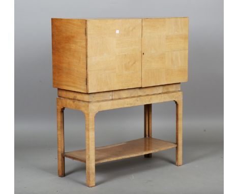 An Art Deco walnut cabinet, in the manner of Gordon Russell, the two doors with geometric veneer, height 92cm, width 77cm, de