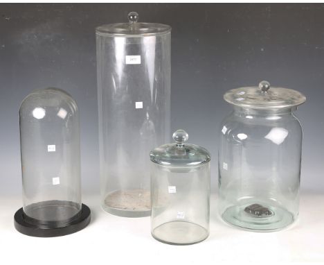 A mid-20th century cylindrical glass jar and cover, height 53cm, a similar smaller example, another jar and associated cover 
