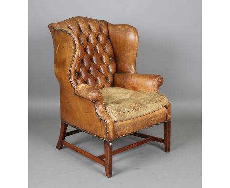 An early/mid-20th century George III style mahogany wing back armchair, upholstered in buttoned brown leather, height 109cm, 