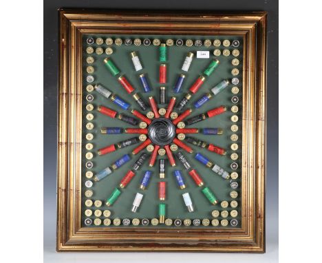 A modern display of shotgun cartridges, centred by a clay pigeon, framed and glazed, 75cm x 65cm.Buyer’s Premium 29.4% (inclu