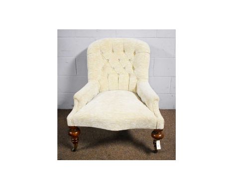 A Victorian button-back armchair, upholstered in a woven cream material, raised on substantial turned oak front legs with bra