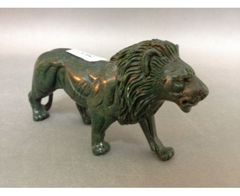 A green hardstone jade style carving of a lion. 