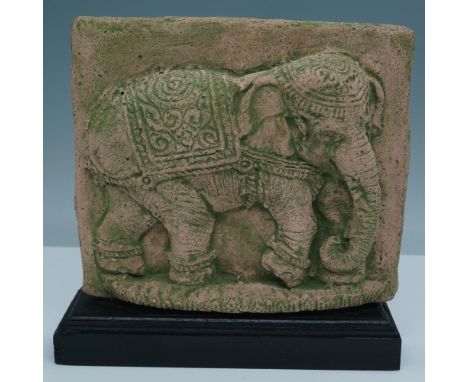 This intricately carved elephant relief sculpture, set on a wooden base, displays a finely detailed depiction of an elephant 