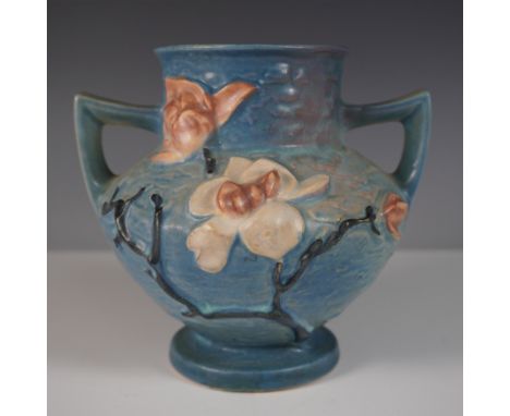 Elegant Roseville Pottery vase in the Magnolia pattern, showcasing a vibrant blue background with raised floral motifs. This 