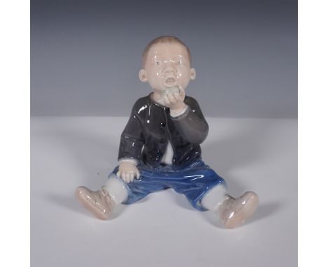 A charming Royal Copenhagen porcelain figurine, model 4538, depicting a young boy seated on the ground, dressed in a dark jac