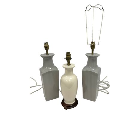 Pair of grey ceramic table lamps, together with another lamp on a wooden plinth