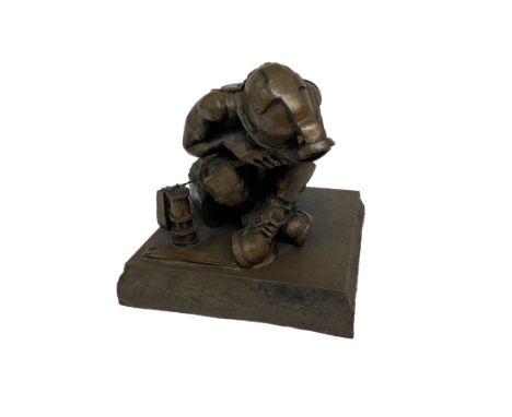 Bronzed cold cast figure of a miner sat beside a lamp by Robert Olley on rocky square plinth base, H17cm