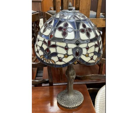 A Tiffany style table lamp with a domed shade in cream, blue and red