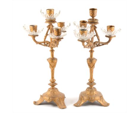 A pair of four-light gilt metal candelabra, with moulded glass drip pans (one missing), 40cm.