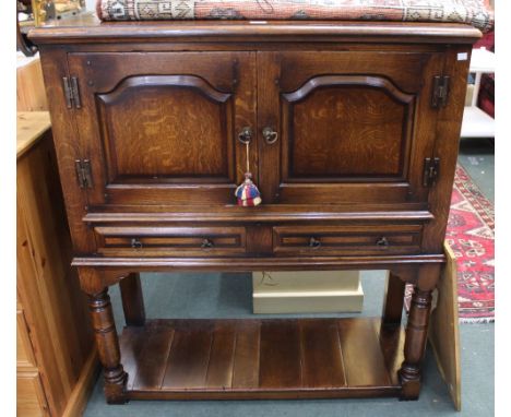 A well made oak reproduction drinks cabinet two doors over two drawers and low shelf low under tier