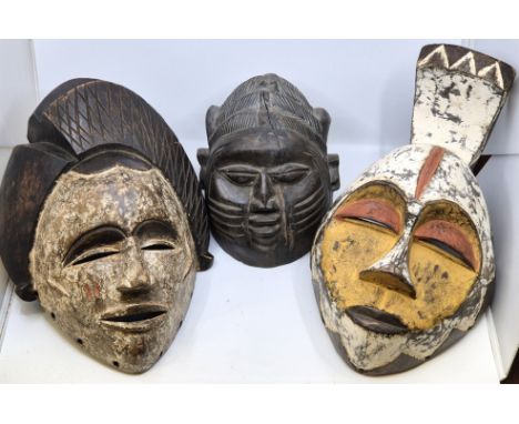 Ethnographica: Three West African carved wood tribal masks, 20th century, two with painted decoration, the largest height 41c