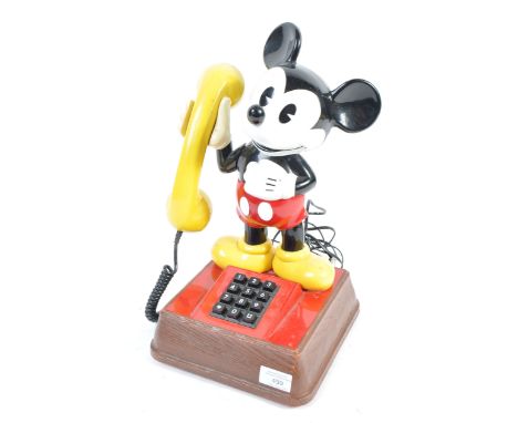 A vintage Walt Disney Mickey Mouse telephone. The top depicting Mickey holding the handset, his arm doubling as the receiver.