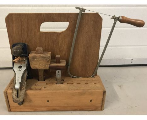 A collection of vintage woodworking tools in handmade wooden tool rack.  To include: plane, mallet and hacksaw. 
