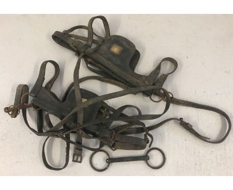 A small collection of vintage horse tack.  2 sets of blinkers with leather straps and a bit. 